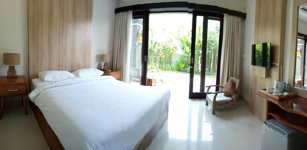 努沙杜瓦雷斯亚旅馆的卧室配有白色的床和滑动玻璃门
