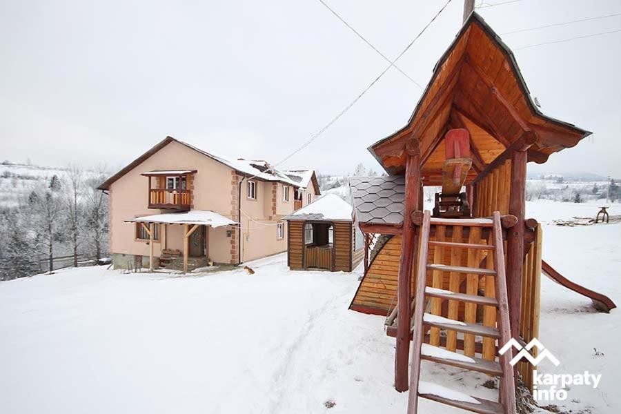 斯拉夫西克на гірському схилі的雪地中带游乐场的小木屋