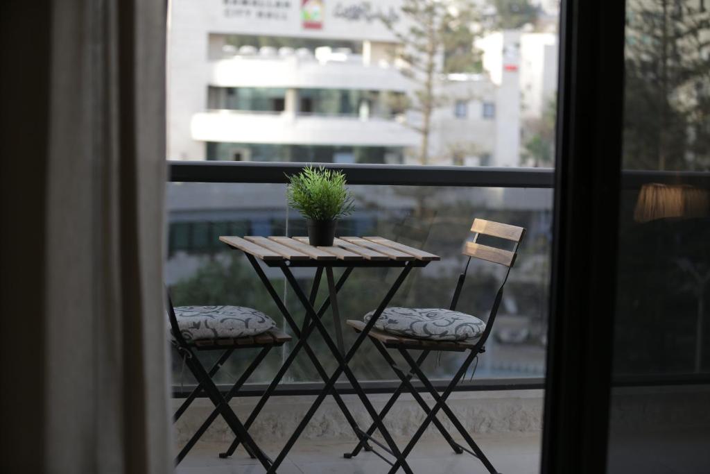 拉马拉Ramallah Modern Apartment的阳台上的桌子、两把椅子和盆栽植物