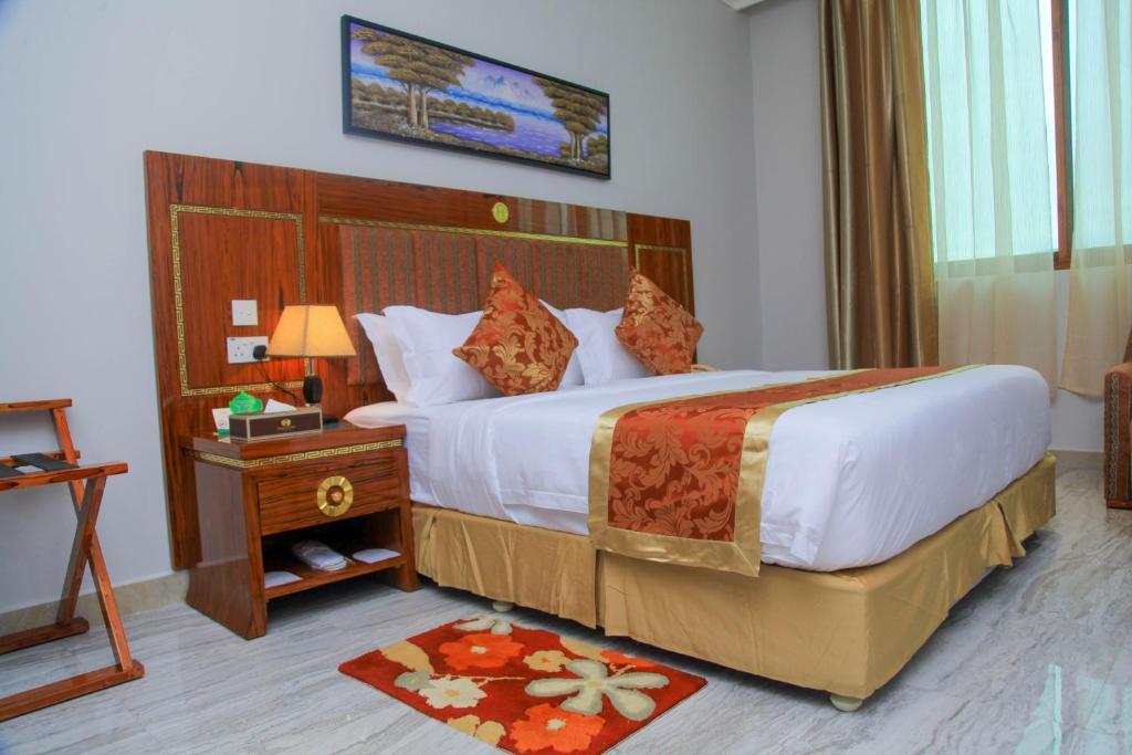 达累斯萨拉姆Tiffany Diamond Hotels LTD - Makunganya的酒店客房设有一张大床和一张桌子。