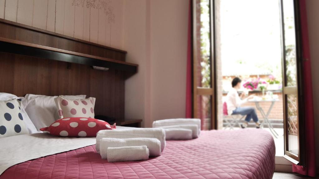 博洛尼亚Hotel EMI的卧室配有带枕头的粉红色床和阳台。
