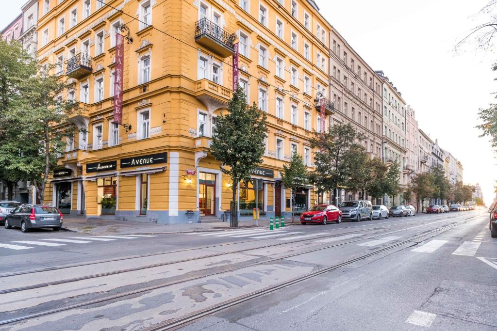 布拉格拉芬尼斯酒店的一条城市街道上的黄色建筑,有车辆停放