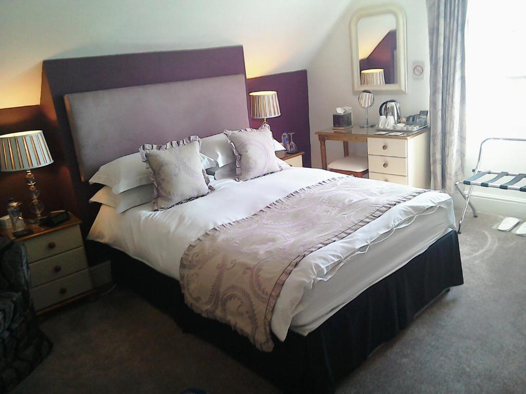 布里德灵顿South Lodge Guest House的卧室配有一张带白色床单和枕头的大床。