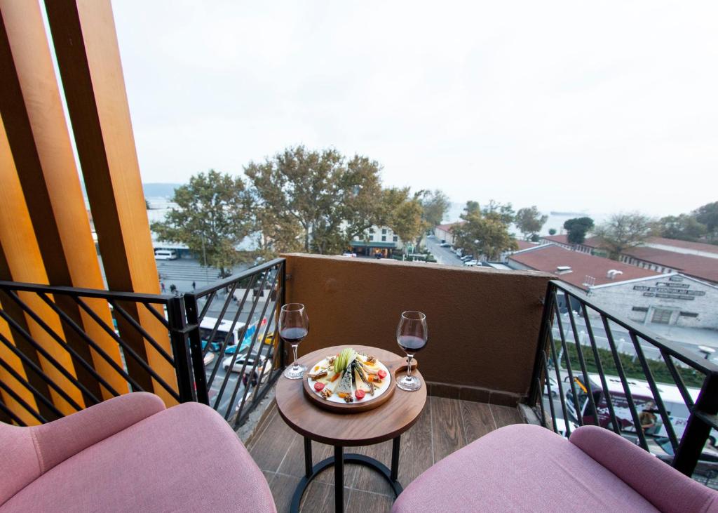 伊斯坦布尔Meydan Besiktas Hotel的阳台配有带一盘食物和酒杯的桌子。