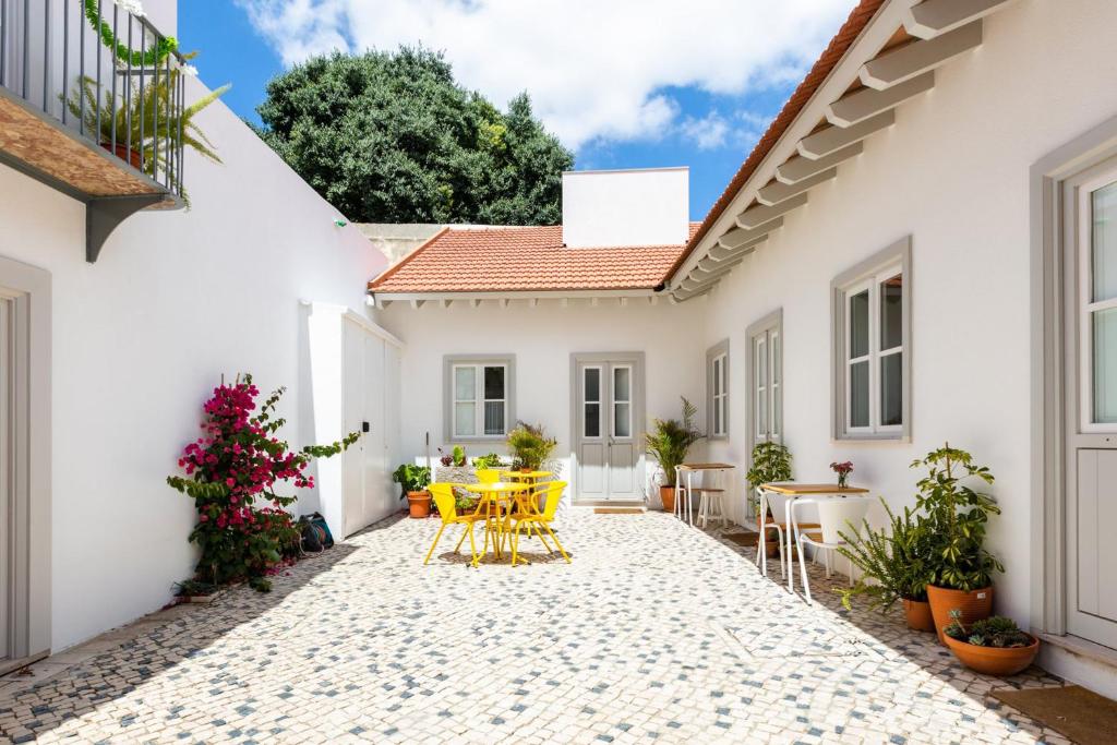 里斯本Patio São Vicente的白色房子的庭院,配有黄色的桌椅