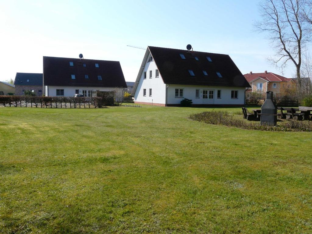 卡尔斯哈根Ferienwohnung Ankerplatz_VOLB的白色的房子,有黑色的屋顶和草地