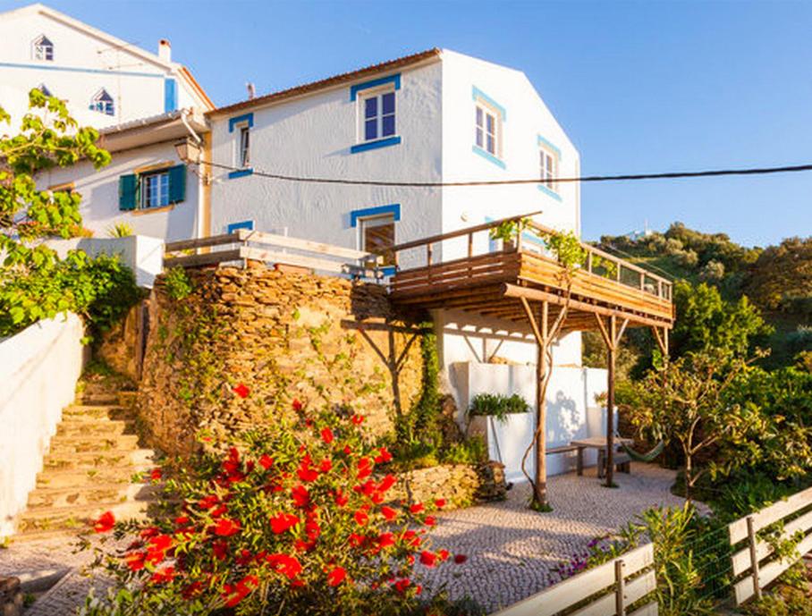 奥德米拉Romantic riverside retreat的带阳台和红色鲜花的白色房屋
