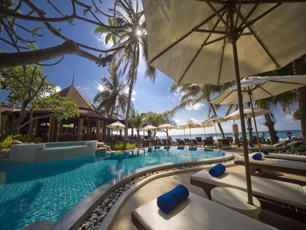 拉迈泰式屋海滩度假酒店的度假村的游泳池配有椅子和遮阳伞