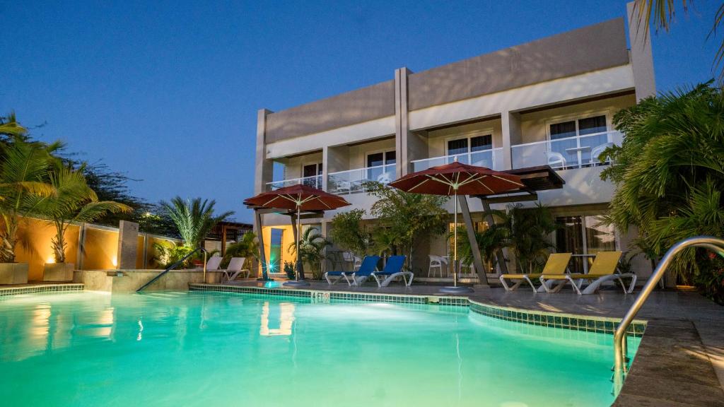 棕榈滩斯梅拉达村海滨度假屋的大楼前的游泳池配有椅子和遮阳伞