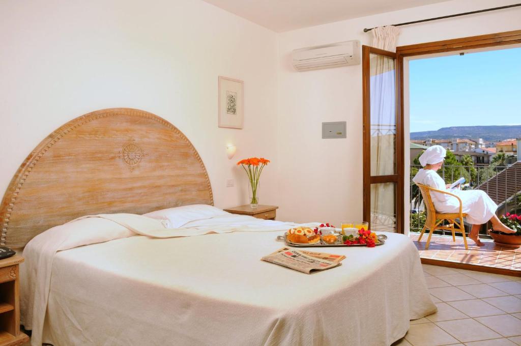 阿尔盖罗安格拉斯酒店的一间卧室,配有一张床上果盘的床