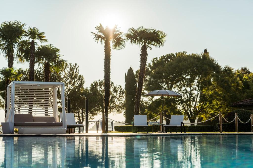 加达湖畔帕登赫美丽海湾豪华Spa度假酒店的一个带椅子的游泳池,棕榈树