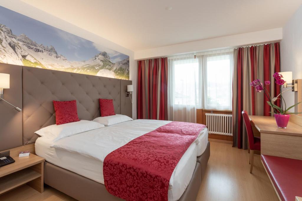 弗利姆斯Hotel Vorab - Kulinarische Vielfalt的酒店客房设有一张大床和一张书桌。