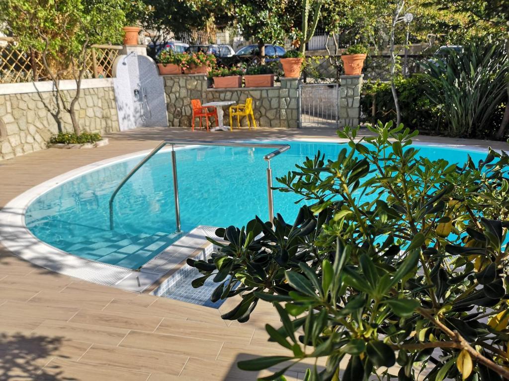 伊斯基亚Aparthotel Villa Marinù的庭院内的游泳池,配有桌椅