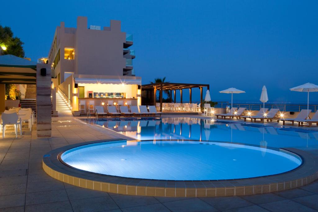 卡法斯Erytha Hotel & Resort Chios的夜间游泳池,配有椅子和遮阳伞