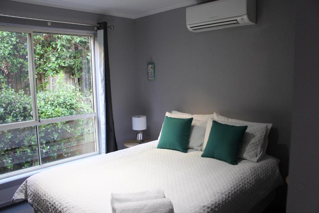 科夫斯港Aqualuna Apartments的一间卧室配有一张带绿色枕头的床和一扇窗户