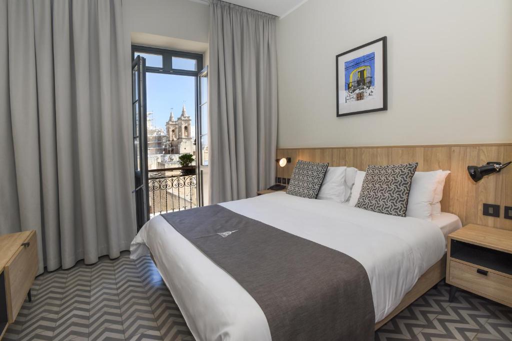 瓦莱塔La Falconeria Hotel的酒店客房设有一张大床和一个阳台。