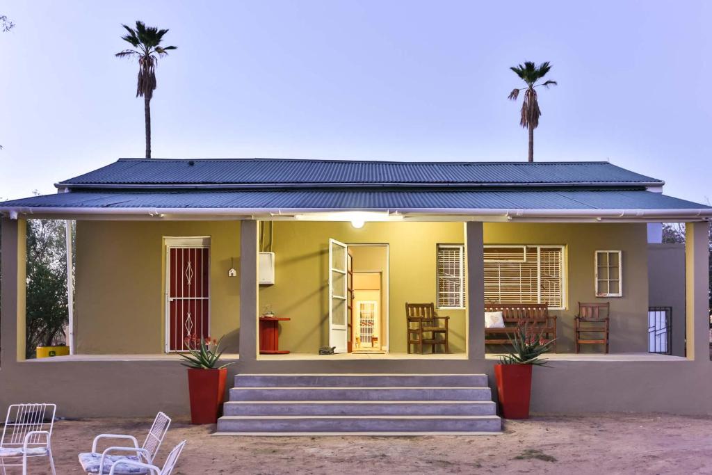 奥茨胡恩Hazenjacht Karoo Lifestyle - Oom Manus se Huis的一座小黄色房子,两棵棕榈树
