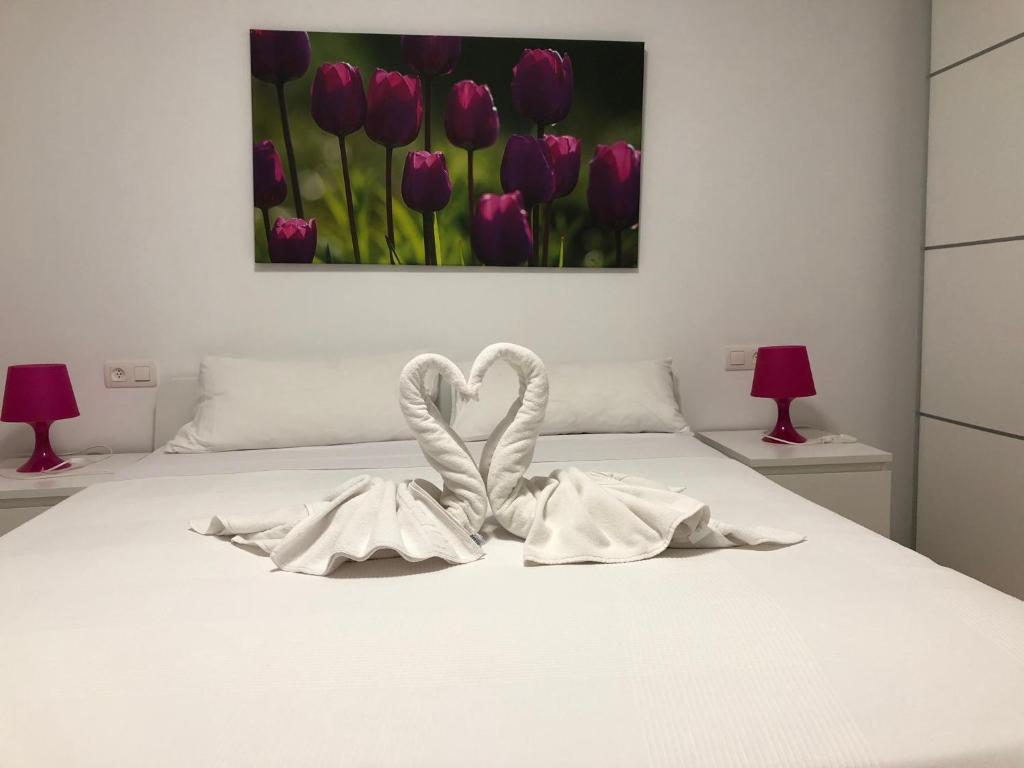 特鲁埃尔Apartamento Centro Historico Teruel的白色的床,有两条白色毛巾,形成心形