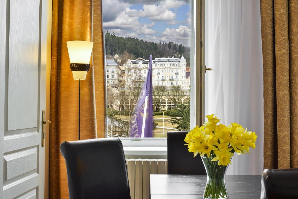 玛丽亚温泉Apartments Central Park Marienbad的窗前桌子上的黄色花瓶