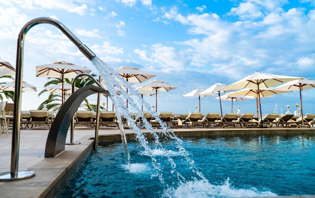 马略卡岛帕尔马尼克斯宫酒店的游泳池中的喷泉,带遮阳伞
