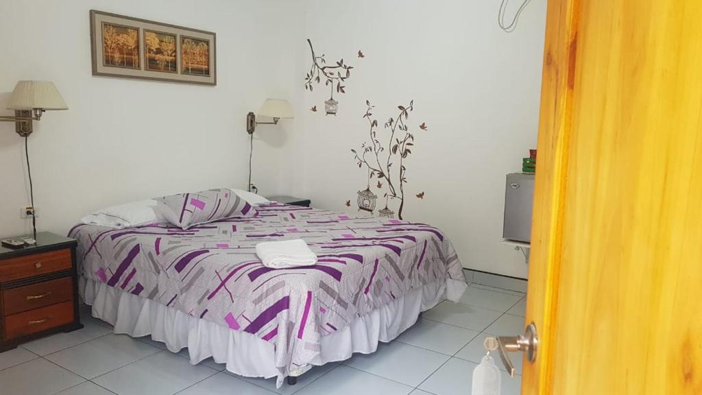 埃斯梅拉达斯Hotel Las Palmas的一间卧室配有一张带紫色和白色毯子的床