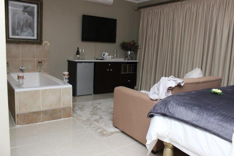 布隆方丹Reliwave Pty Ltd的一间卧室配有一张床、一个浴缸和一台电视。