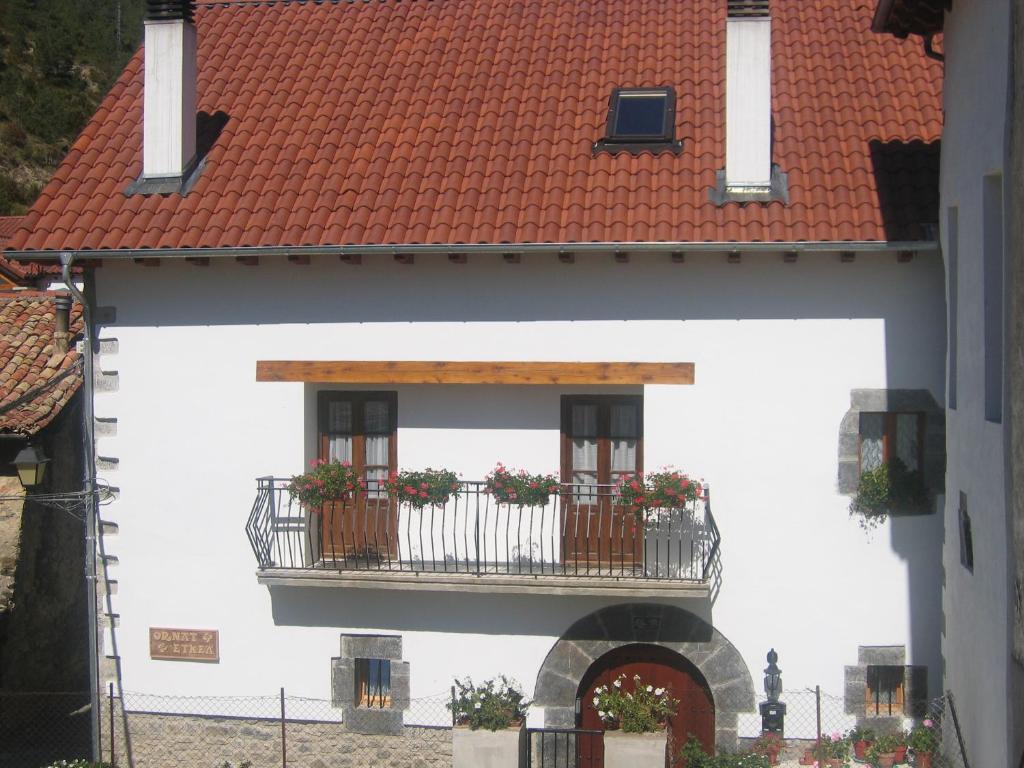 VidángozCasa rural Ornat Etxea的带阳台和红色屋顶的白色建筑