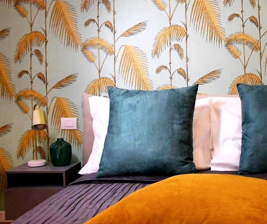 米兰Serendipity Apartments - Duomo的一间卧室配有一张带蓝色枕头的床和热带壁纸