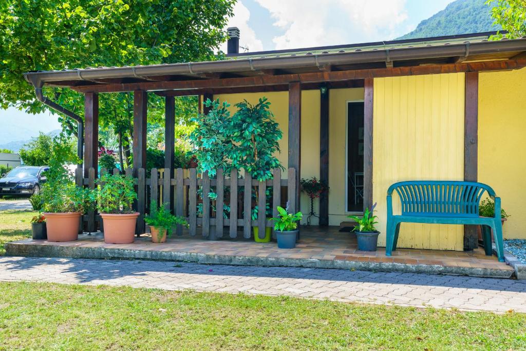 多马索bungalow campeggio madonnina的坐在带盆栽的门廊上的蓝色长椅