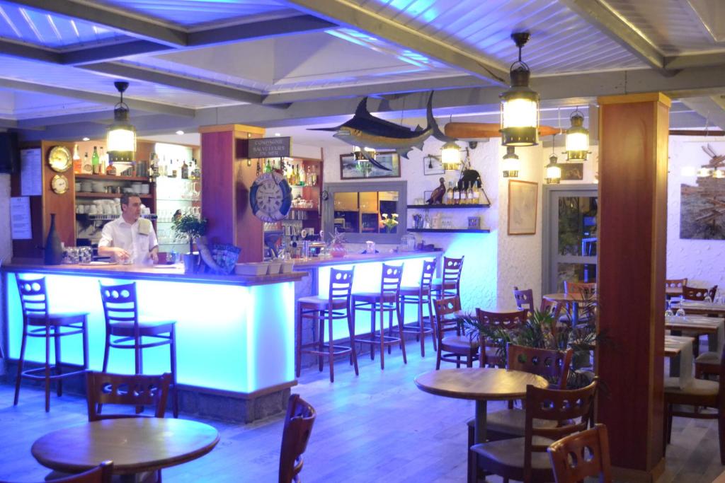 圣皮耶尔基贝龙Hotel De Bretagne的餐厅内的酒吧配有桌椅