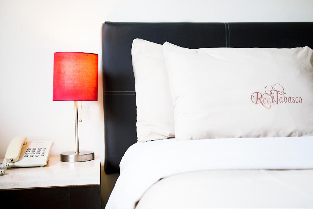 比亚埃尔莫萨Suites Real Tabasco的一间卧室配有一张床、一部电话和一盏灯