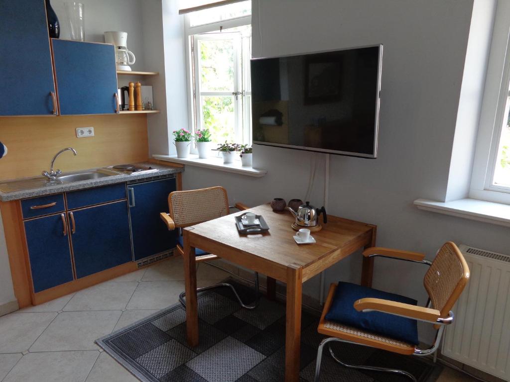 克鲁姆赫恩Apartment Muschel im Gästehaus Heeren的厨房配有木桌和墙上的电视。