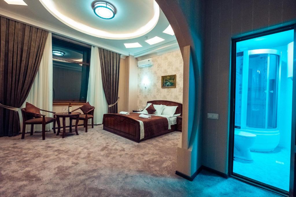 撒马尔罕Meros Boutique Hotel的酒店客房带一张床、一张桌子和椅子