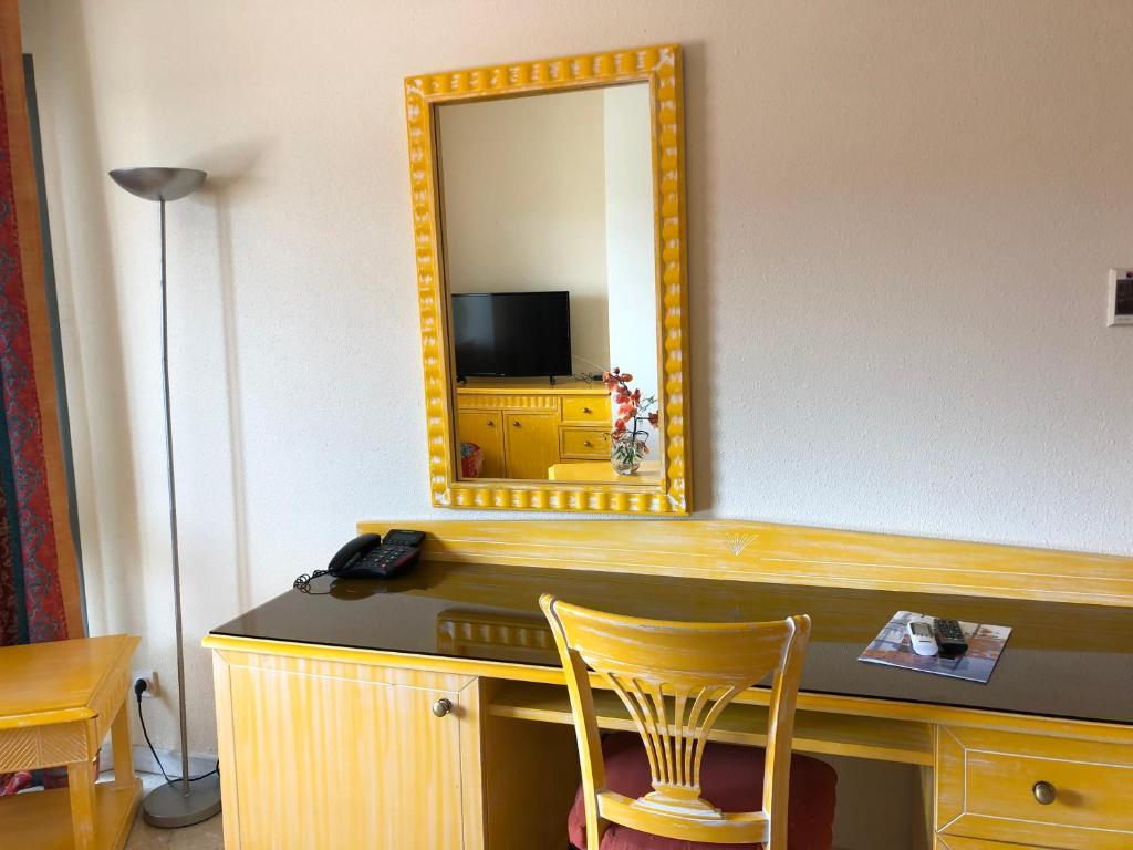 勒拉芒坦Hotel La Galleria的镜子和一张桌子及椅子