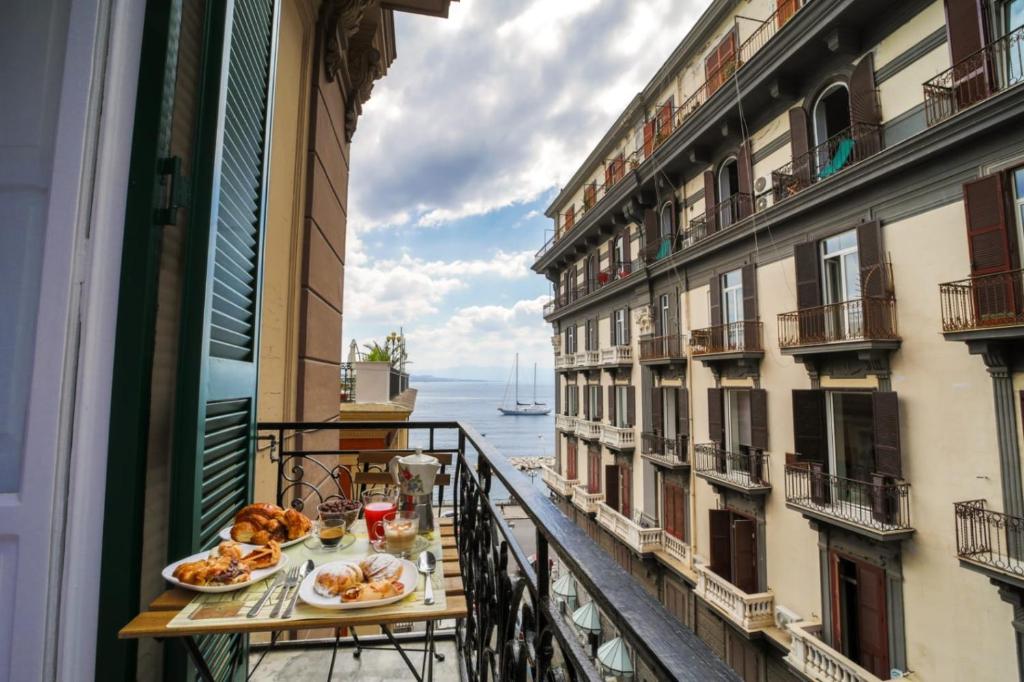 那不勒斯迪帕尔马套房旅馆的阳台配有餐桌,享有水景