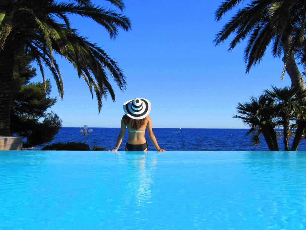 圣拉斐尔摩尔人的别墅酒店的站在一个游泳池的头顶上看着大海的女人