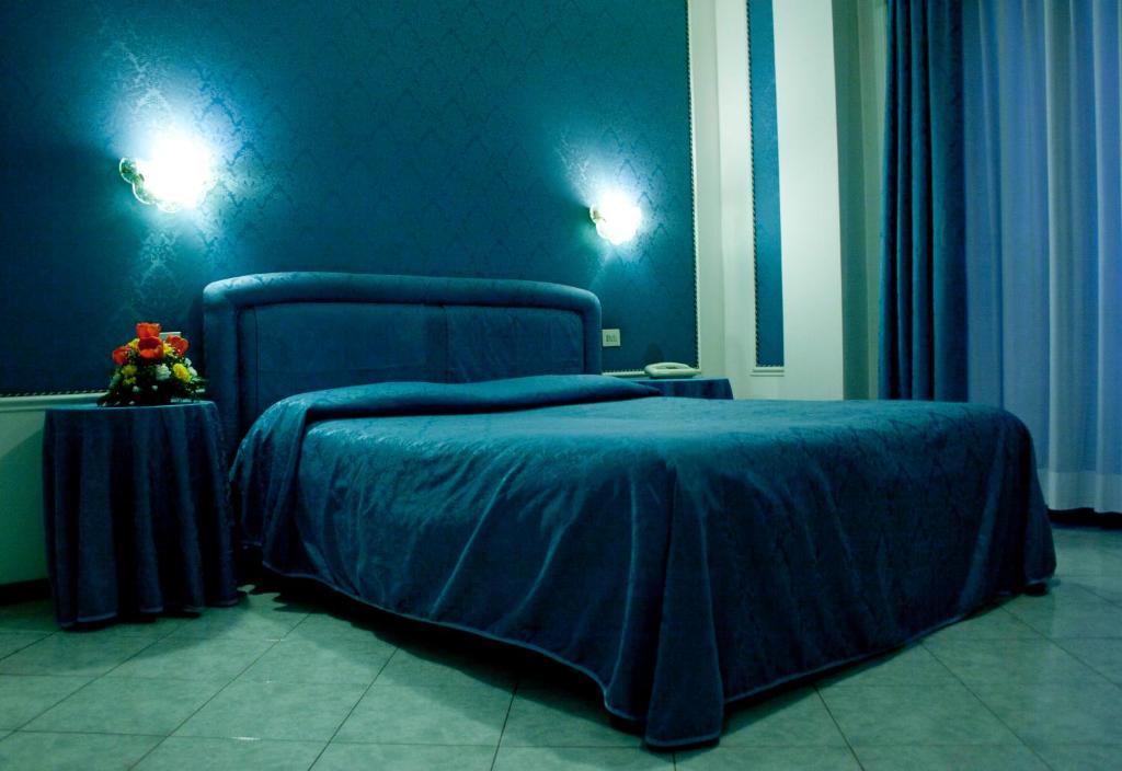 雷扎托米开朗基罗酒店的蓝色的卧室,配有床和鲜花桌