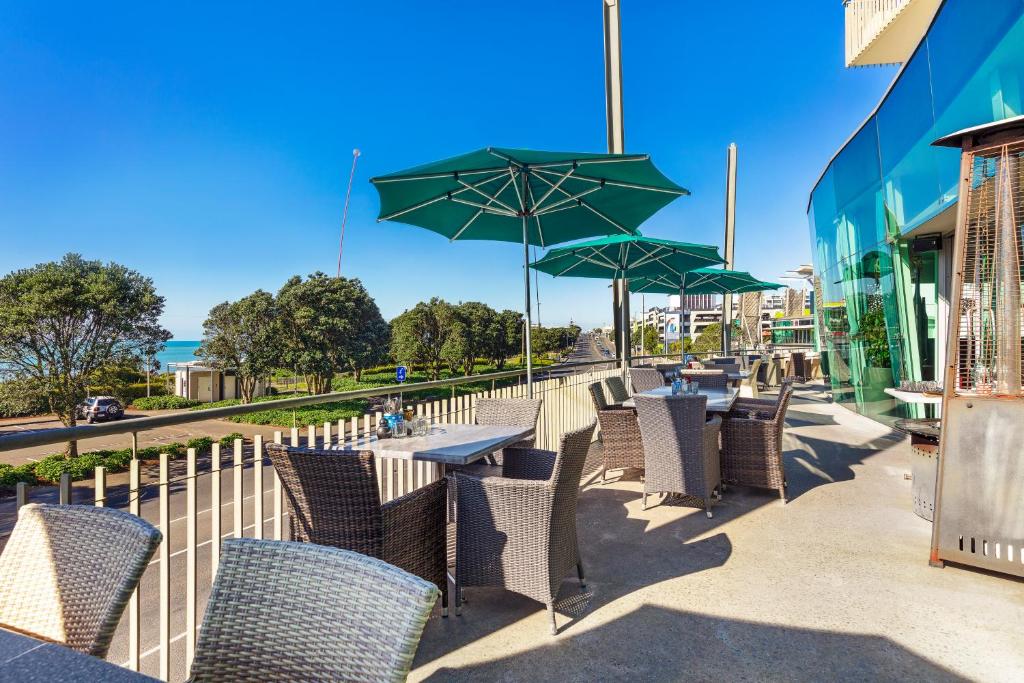 新普利茅斯新普利茅斯海滨千禧酒店的一排带绿伞的桌椅