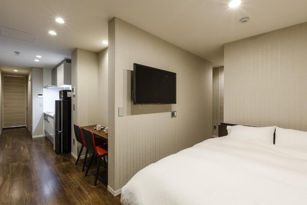 京都Kyo no yado en的酒店客房配有一张床、一张书桌和一台电视。