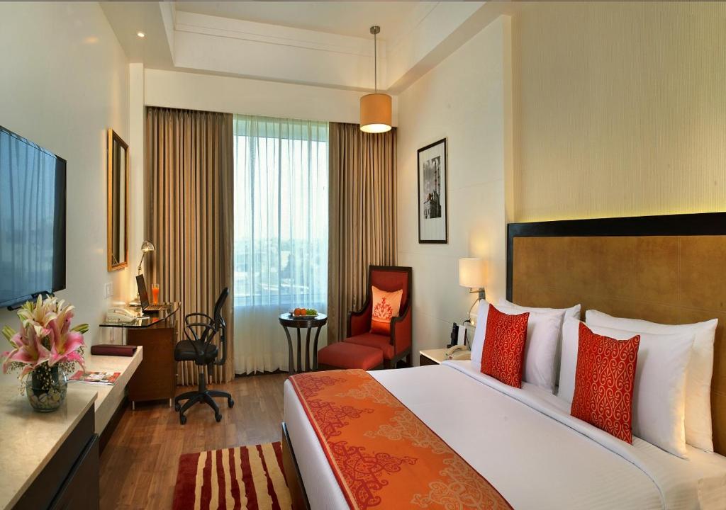 拉杰果德Fortune Park JPS Grand, Rajkot - Member ITC's Hotel Group的酒店客房带一张大床和一把椅子