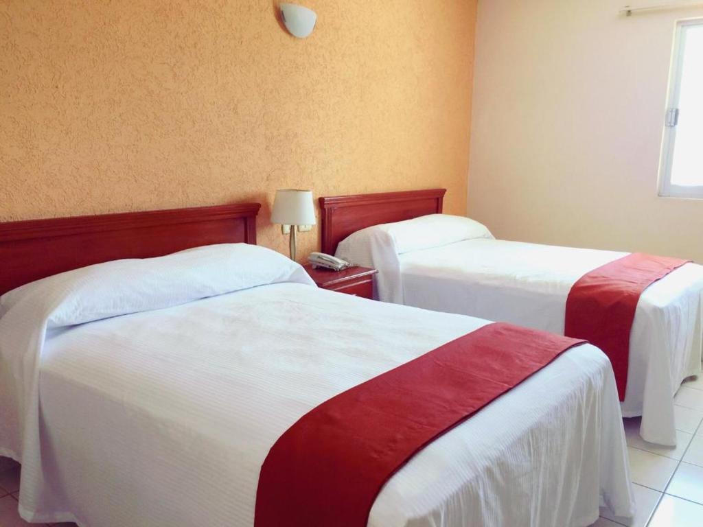 坎佩切Hotel Villa Campeche的酒店客房带两张红色和白色的床单
