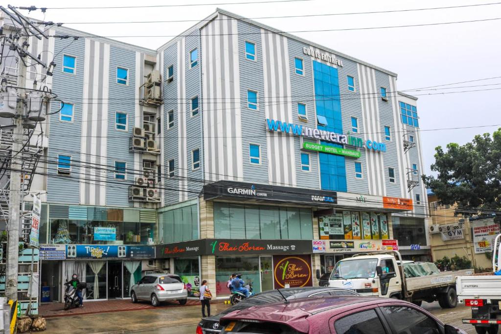 宿务RedDoorz Plus New Era Budget Hotel Mandaue former RedDoorz Plus near UV Mandaue Cebu的城市街道上一座大型建筑,有汽车