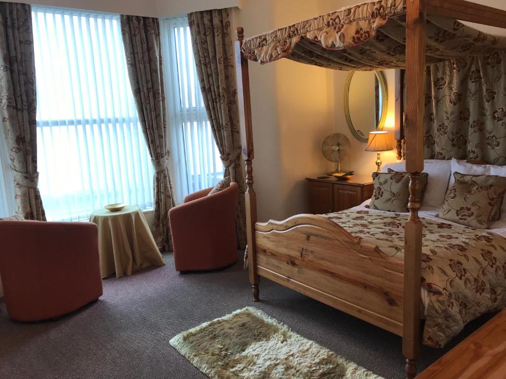 布莱克浦贝尔蒙特酒店的一间卧室配有一张天蓬床和两把椅子