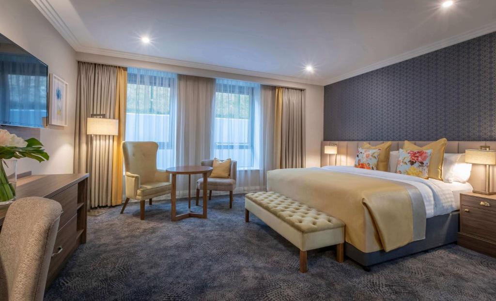 利默里克Castletroy Park Hotel Suites的酒店客房带一张床、一张桌子和椅子