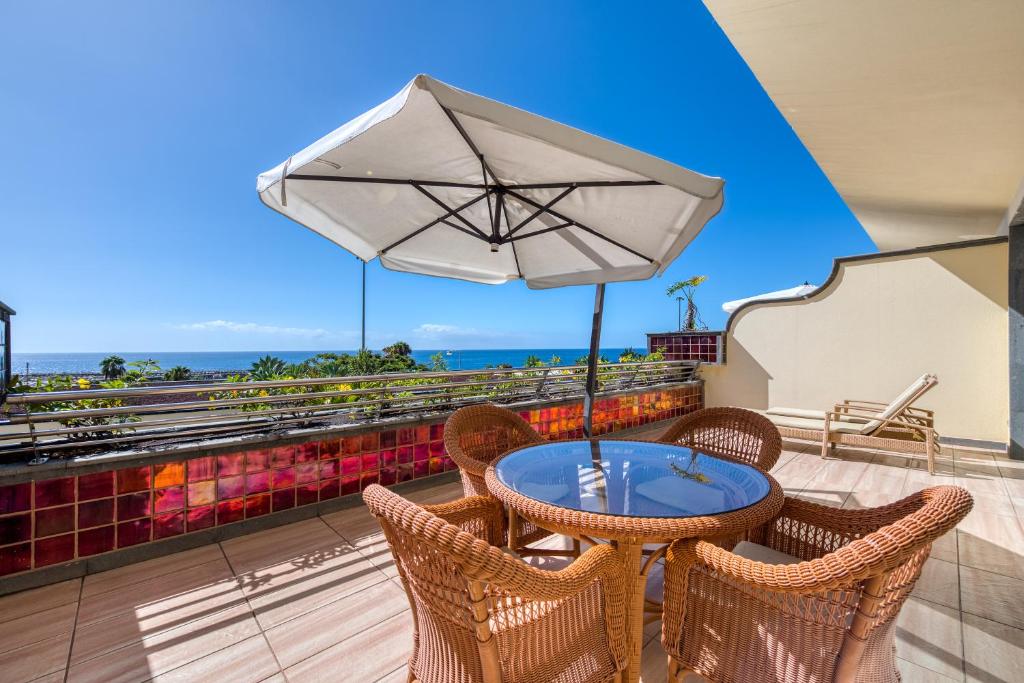阿马多雷斯Holiday Club Playa Amadores的阳台配有桌椅和遮阳伞
