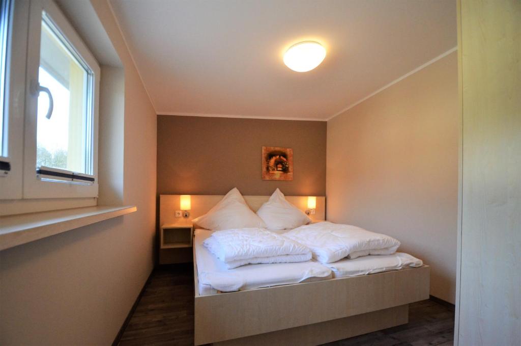 格拉尔-米里茨Ferienwohnungen Graal-Müritz的一间卧室配有一张带白色床单的床和一扇窗户。