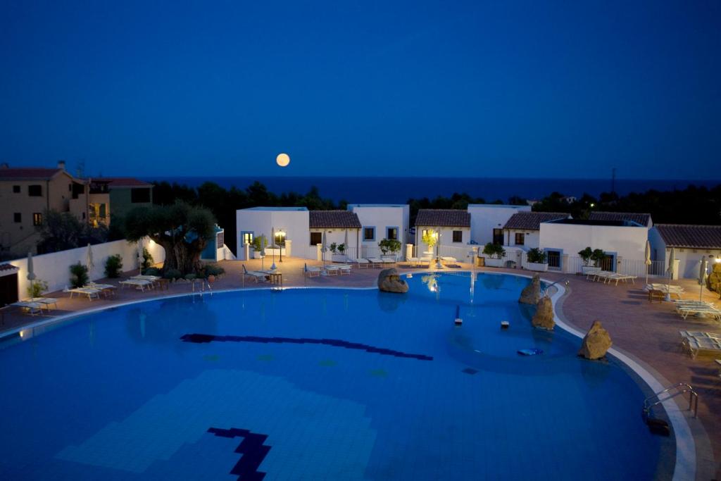 卡拉古诺内Hotel Resort Nuraghe Arvu的一座大型游泳池,晚上有月亮,