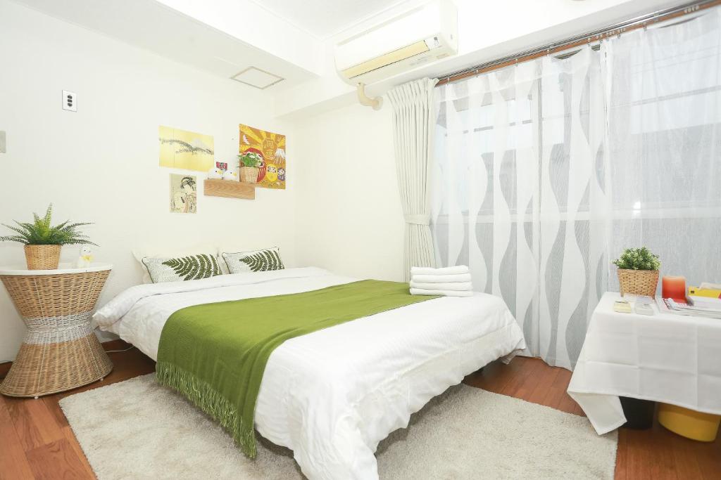 东京Spring Apartment Shinjuku的一间卧室配有一张带绿毯的床和窗户。