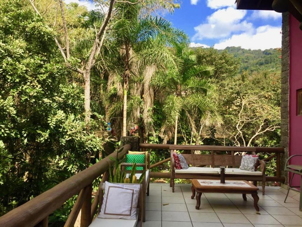伊利亚贝拉Villa Cachoeira da Rocha的阳台配有桌椅和树木。