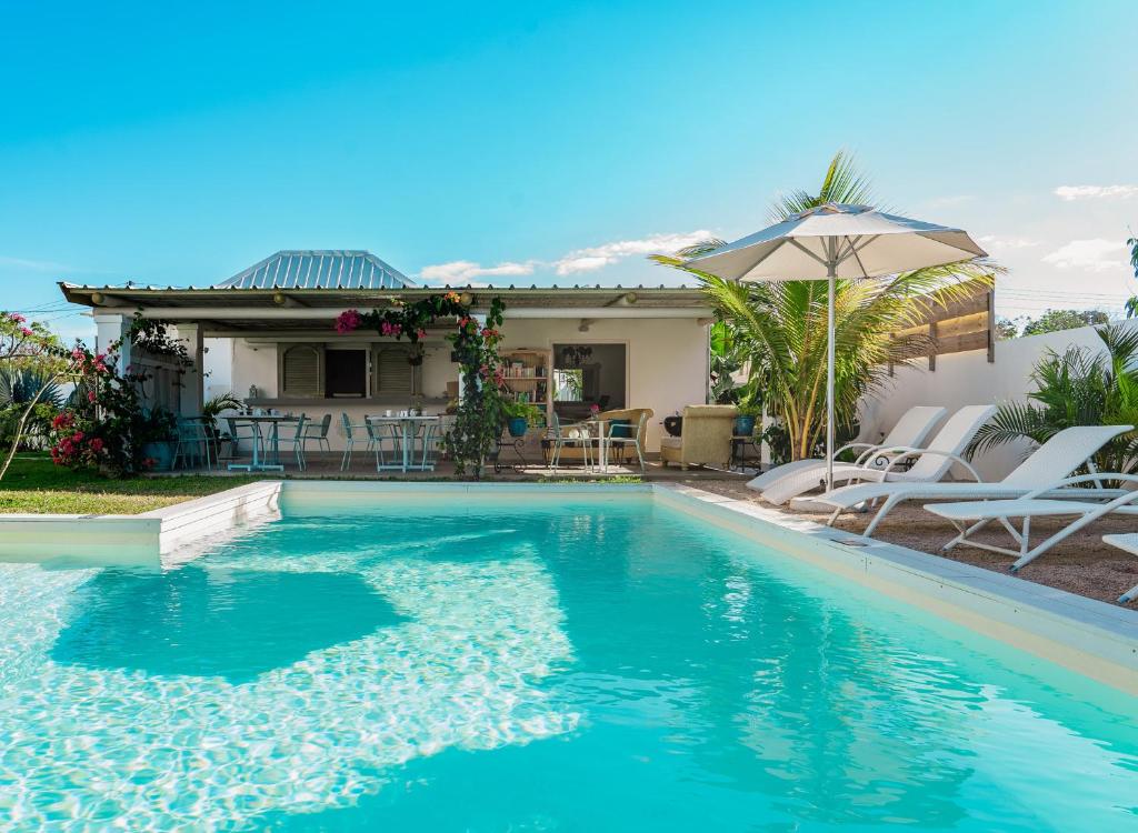 康隆尼角曼荼罗莫里斯度假屋的房屋旁的游泳池配有椅子和遮阳伞